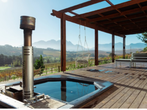A Carbo III Wood Fired Hot tub on a deck overlooking mountains.