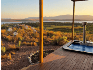 A Carbo III Wood Fired Hot tub on a deck overlooking a lake.