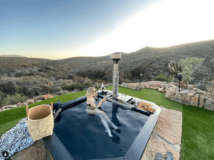 A woman enjoying sparkling wine in a Carbo III Wood Fired Hot tub.