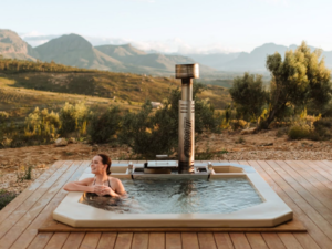A Carbo III Wood Fired Hot tub on a deck with a woman inside the tub.