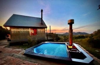 A A Carbo III Wood Fired Hot tub at night with a cottage in the background.