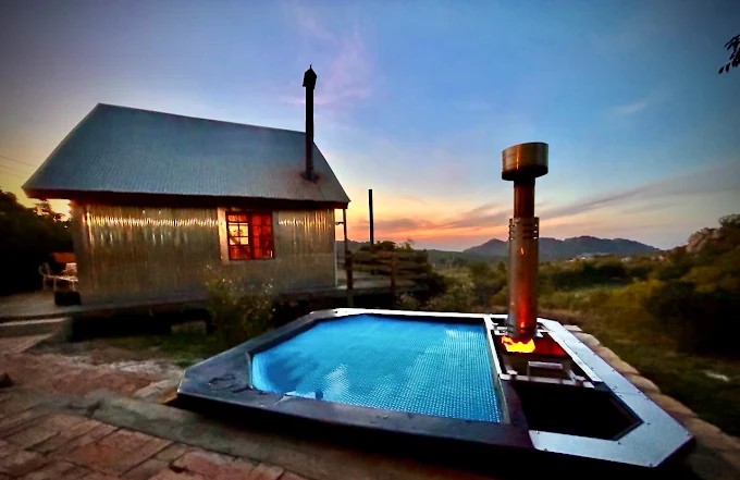 A A Carbo III Wood Fired Hot tub at night with a cottage in the background.